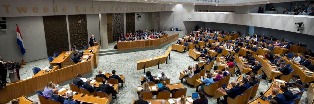 Overzicht van de plenaire zaal met Kamerleden in de zetels en kabinetsleden in vak K.