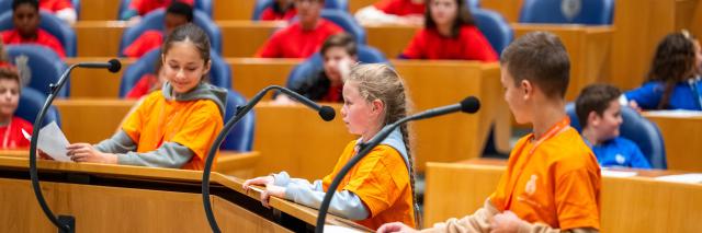 drie basisschoolleerlingen staan achter de interruptiemicrofoon 