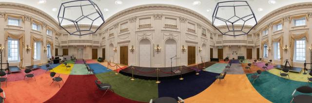 Panorama van de Oude Zaal, met gekleurde vloerbedekking en moderne kroonluchters.