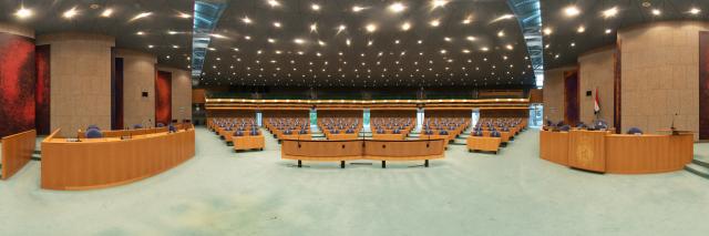 Panorama van de Plenaire Zaal, met bankjes, spreekgestoelten en plafond.