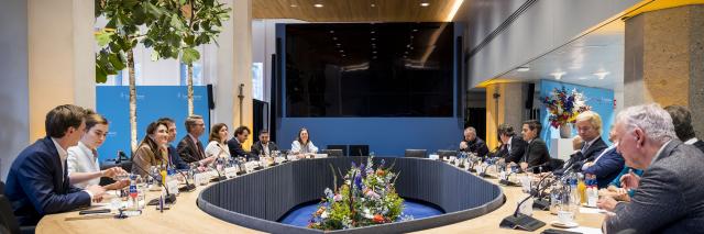 Rond de houten ovale tafel in de Max van der Stoelzaal zijn alle lijsttrekkers zichtbaar en Kamervoorzitter Martin Bosma.  