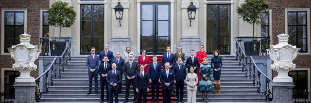 De nieuwe ministers staan verspreid rond Koning Willem-Alexander op de trappen van Paleis Huis ten Bosch. 