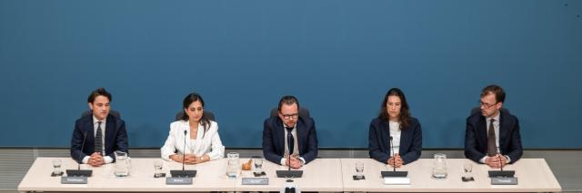 Voltallige commissie, vijf mensen, op een rij achter de tafels in de Enquêtezaal. 