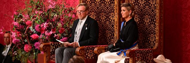 Koning Willem-Alexander en koningin Máxima in de Koninklijke Schouwburg van opzij gefotografeerd, terwijl de Koning de troonrede voorleest.