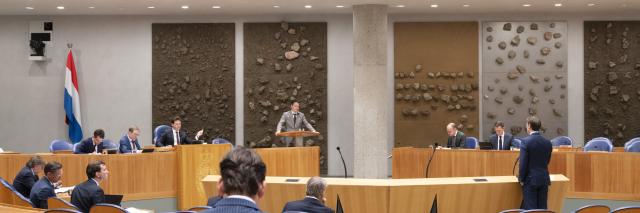 Kamerlid Henk-Jan Oosterhuis staat achter het spreekgestoelte in de plenaire zaal van de Tweede Kamer. Naast hem zit Kamervoorzitter Thom van Campen. In vak K zitten minister Eelco Heinen en Eelco Eerenberg.