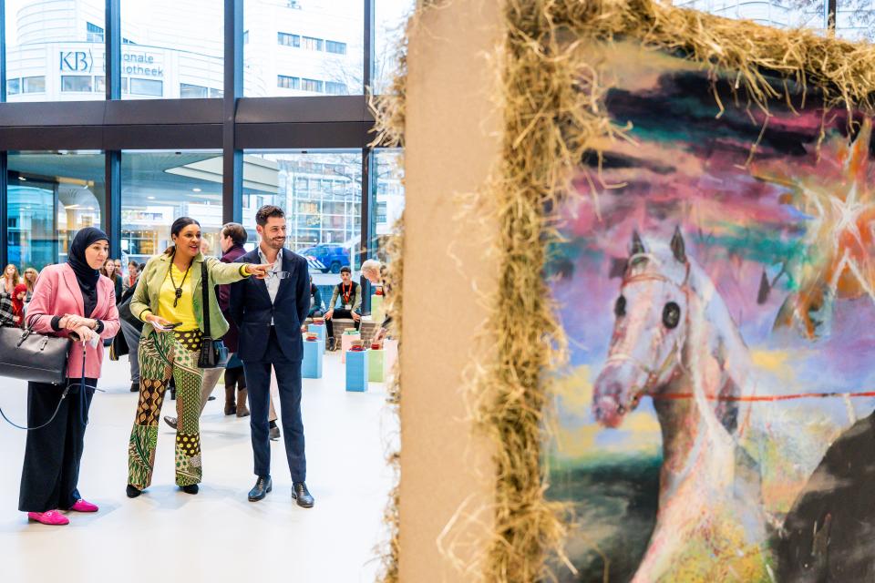 Enkele Kamerleden wijzen naar een kunstwerk in de Statenpassage.