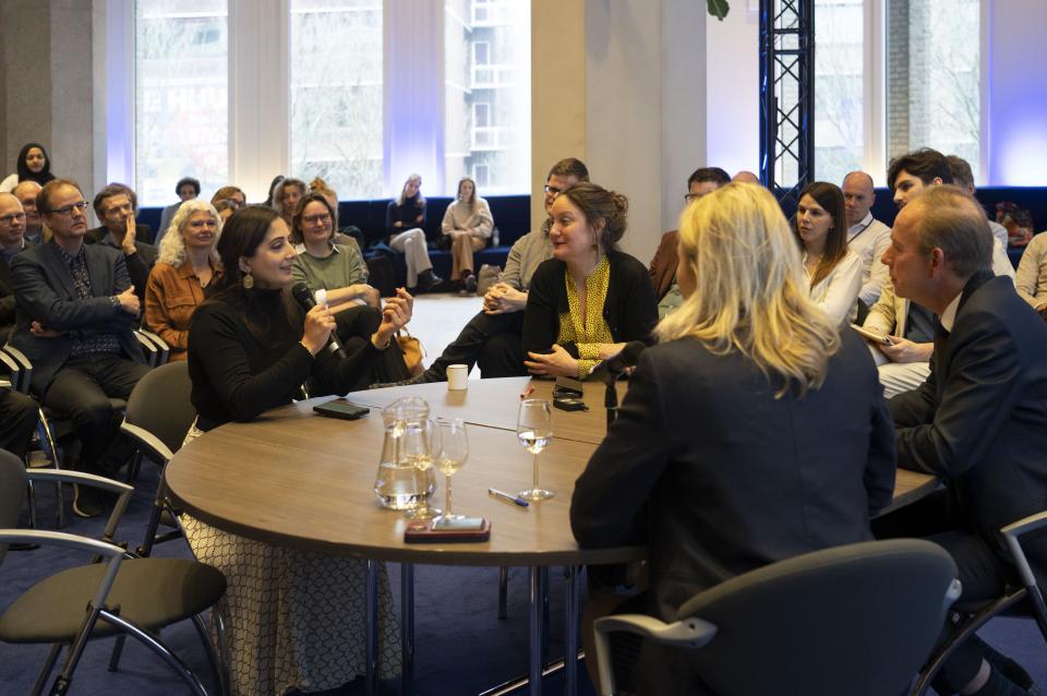 Drie Kamerleden aan een tafel in het midden van een zaal waarin mensen toekijken. PvdA-Kamerlid Songül Mutluer heeft de microfoon en vertelt over haar ervaringen aan tafel met de Kamerleden Kees van der Staaij (ChristenUnie) en Queeny Rajkowski (VVD).