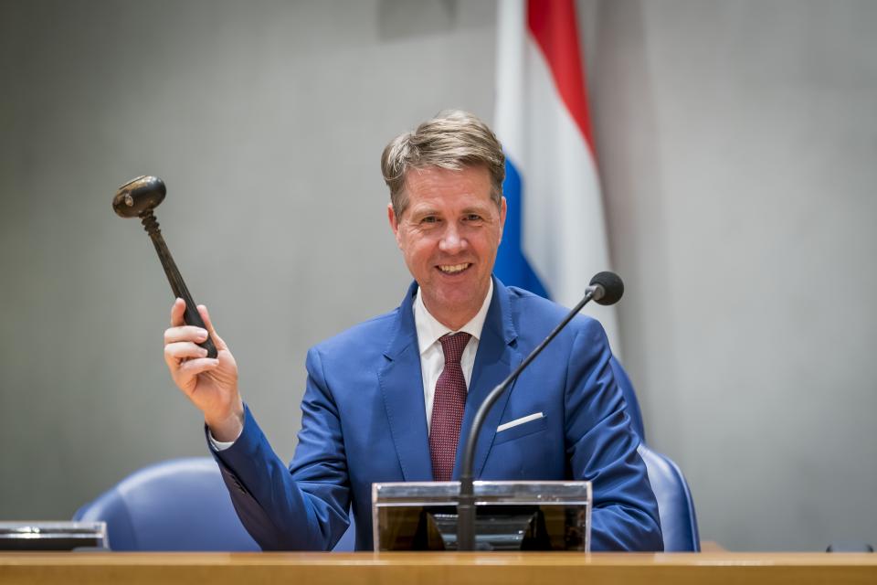 Nieuwe Kamervoorzitter in zijn spreekgestoelte heft de voorzittershamer. Achter hem de Nederlandse vlag.