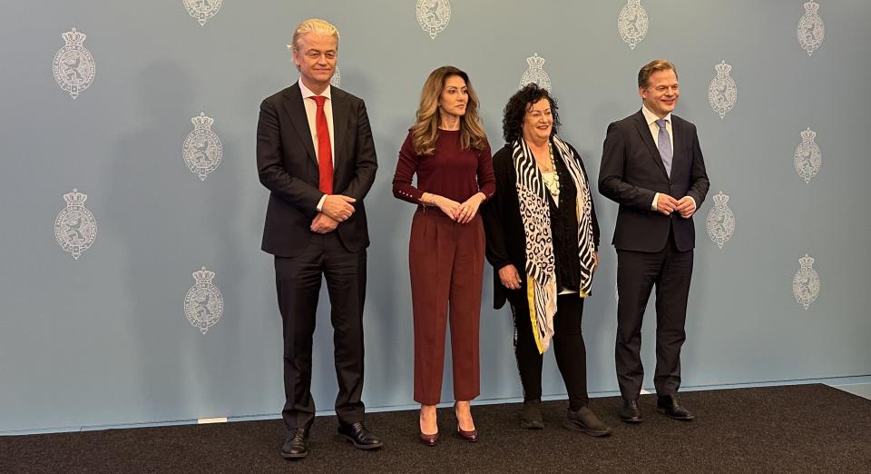 De vier fractievoorzitters poseren staand op een podium voor een griijze wand met daarop meerdere keren het wapen van de Tweede Kamer afgebeeld. Van links naar rechts Geert Wilders (PVV), Dilan Yeşilgöz (VVD), Caroline van der Plas (BBB) en Pieter Omtzigt (NSC).