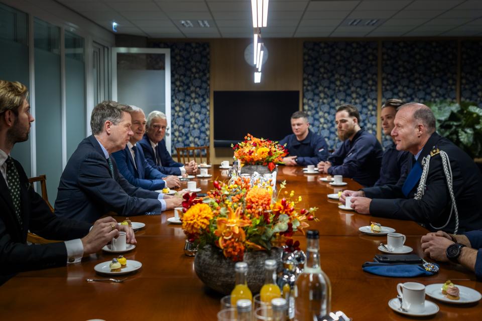 Voorzitter Bosma aan een lange tafel in gesprek met een zeven Koninklijke Marechaussee leden van de 