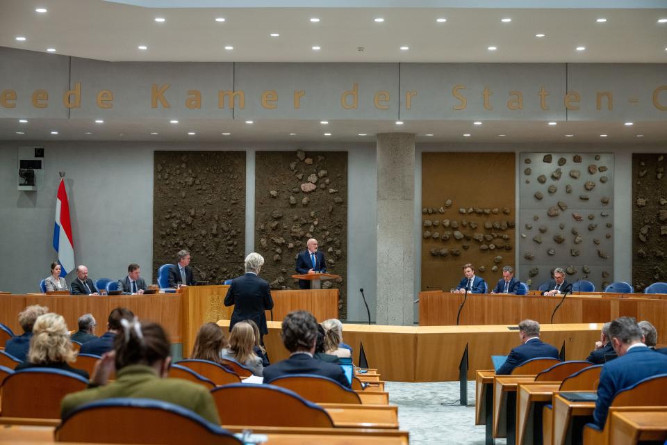 Beeld van de plenaire zaal, van achteren gefotografeerd. Op de rug gezien PVV-fractievoorzitter Geert Wilders bij de interruptiemicrofoon en GroenLinks-PvdA-fractievoorzitter Frans Timmermans achter het spreekgestoelte.