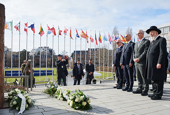 Kranslegging bij het Holocaust monument. De leden van de Assemblee stonden stil bij de bevrijding van Auschwitz-Birkenau 80 jaar geleden. Op de achtergrond zijn de vlaggen van de landen van Europa te zien.
