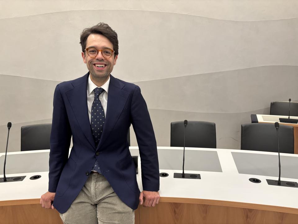 Adjunct-griffier Rick van der Steur leunt tegen de tafel in een commissiezaal.