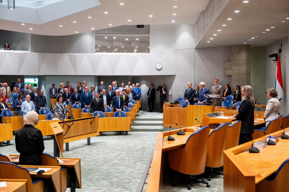 Alle Tweede Kamerleden staan achter hun zetel in de plenaire zaal. In vak K staan vicepremier Fleur Agema en minister Marjolein Faber.