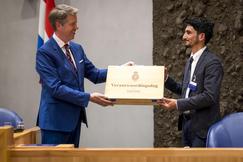 Voorzitter Martin Bosma ontvangt het koffertje van een van de deelnemers van de V-100