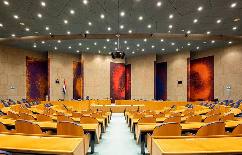 De achterwand van de Plenaire Zaal met daarop een kunstwerk van felgekleurde panelen.