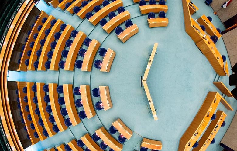 Bovenaanzicht van de Plenaire Zaal, waarin de stoelen in een halfronde vorm staan opgesteld.