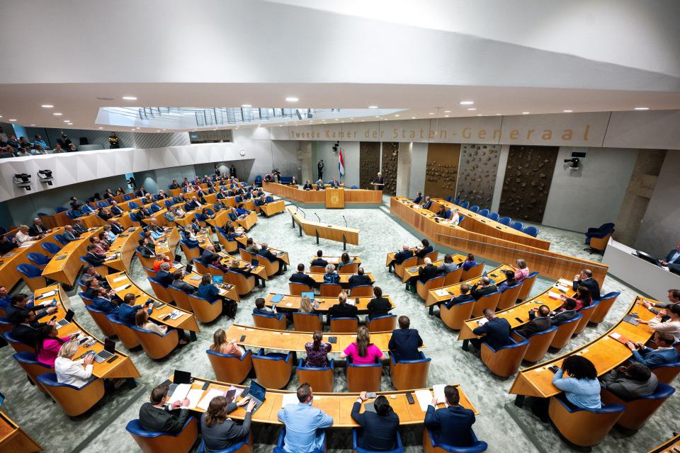 Overzichtsfoto van volle plenaire zaal van bovenaf, vrijwel alle zetels zijn bezet en in het zogeheten vak K zitten minister-president Schoof en de vicepremiers.