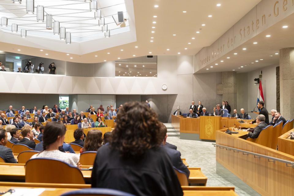 De Oekraïense president Volodymyr Zelensky spreekt in de plenaire zaal van de Tweede Kamer vanuit vak K. Zittende Kamerleden kijken toe..