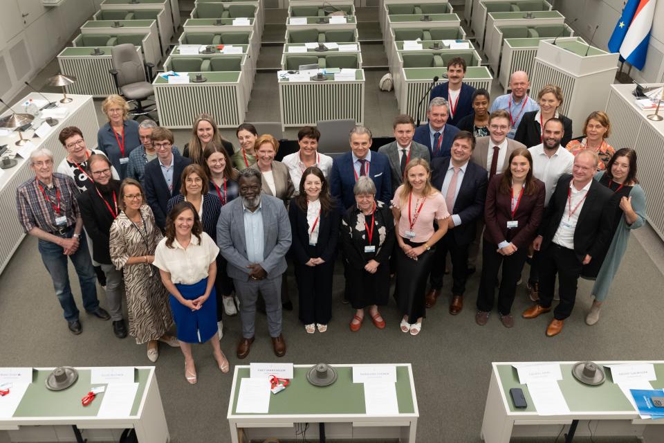 Op de foto staan alle deelnemers in de plenaire zaal van de Eerste Kamer.