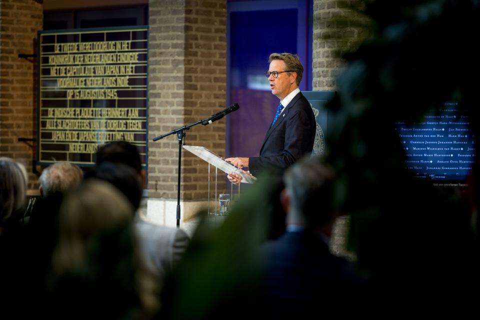 Kamervoorzitter Martin Bosma rechts achter de microfoon, links de tekst die bij de Indische plaquette hoort. Op de voorgrond de aanwezigen van achteren gefotografeerd.