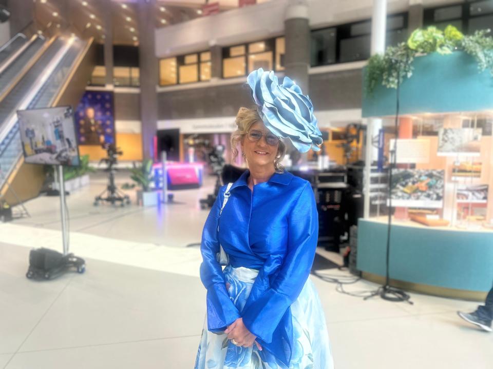 Kamerlid Rachel van Meetelen (PVV) draagt verschillende kleuren blauw, schuin op haar hoofd een hoed. Zij staat voor een ook blauwe vitrine in de Statenpassage van de Tweede Kamer. 