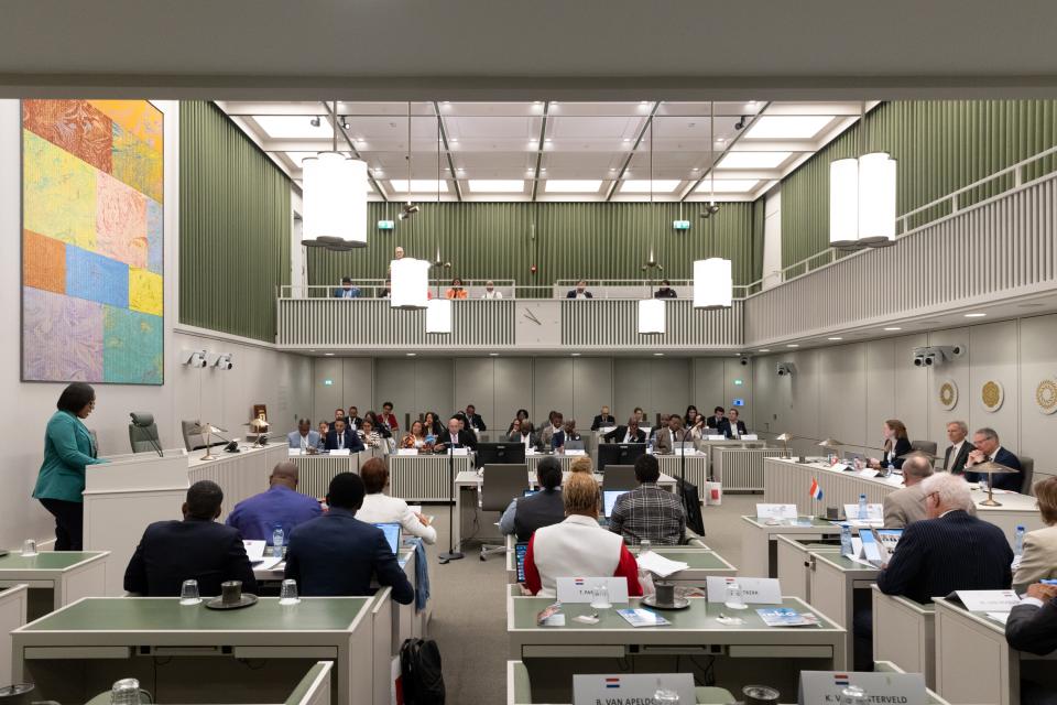 Beeld uit de plenaire zaal van de Eerste Kamer met mensen in de bankjes.