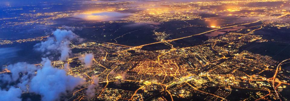 Een luchtfoto van Nederland in de nacht. Je ziet overal lichtjes van de stad.