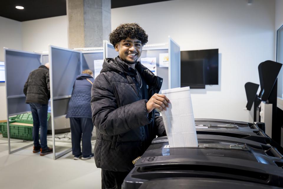 Een jongen stopt zijn stembiljet in de stembus.
