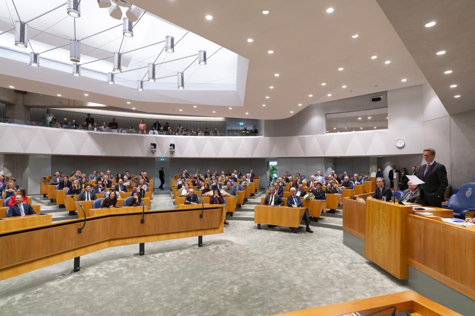 Kamervoorzitter Martin Bosma staat achter zijn tafel met een blad papier in de hand. Links van hem een breed beeld van de plenaire zaal. 