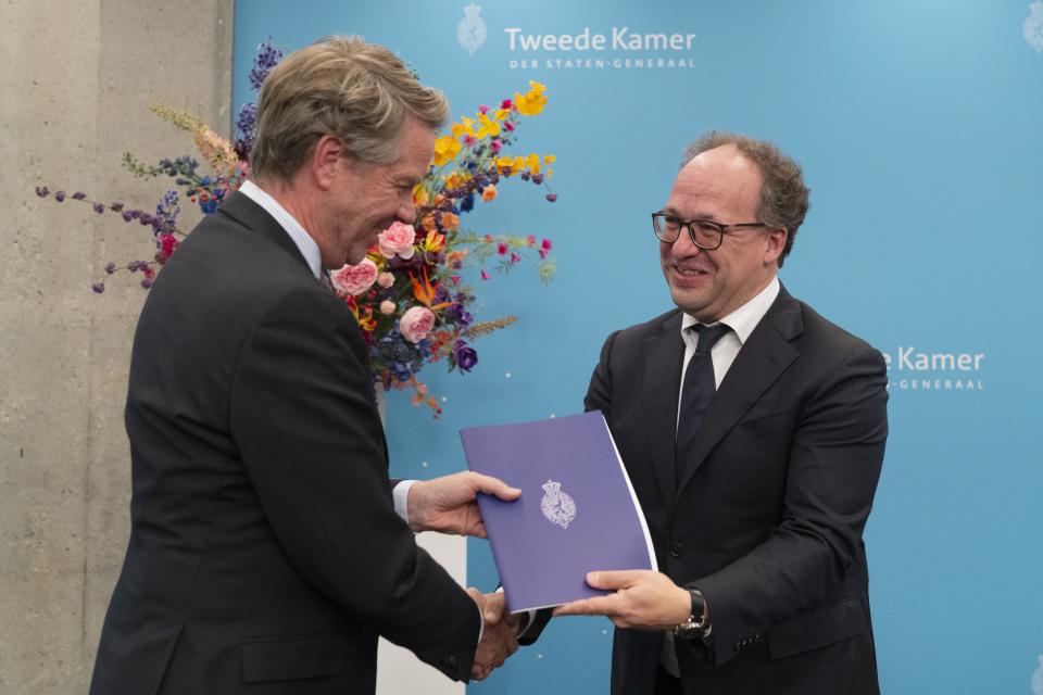 Voor een lichtblauwe achterwand en een bloemstuk overhandigt verkenner Koolmees het verslag aan Kamervoorzitter Martin Bosma. 