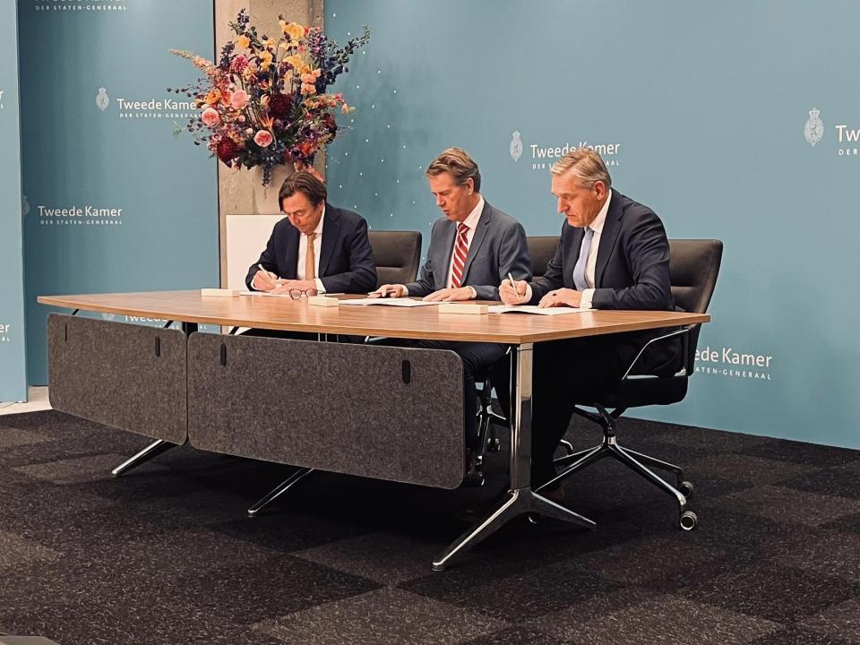 Drie heren naast elkaar achter een tafel, Kamervoorzitter Bosma in het midden. De informateurs tekenen ieder de opdracht. 