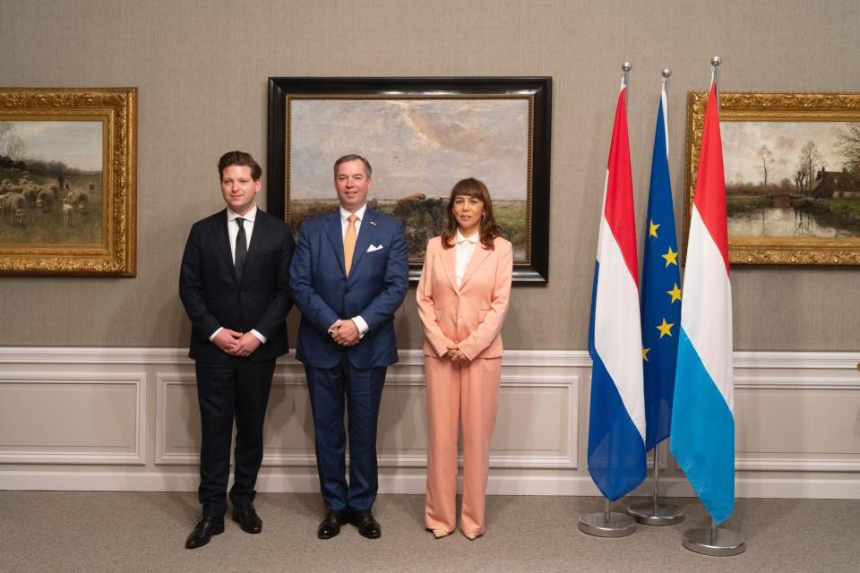 Kamervoorzitter Thom van der Lee, de Groothertog van Luxemburg en Mei Li Vos staan naast elkaar. Naast hen de Nederlandse vlag, de vlag van de Europese Unie en de Luxemburgse vlag.