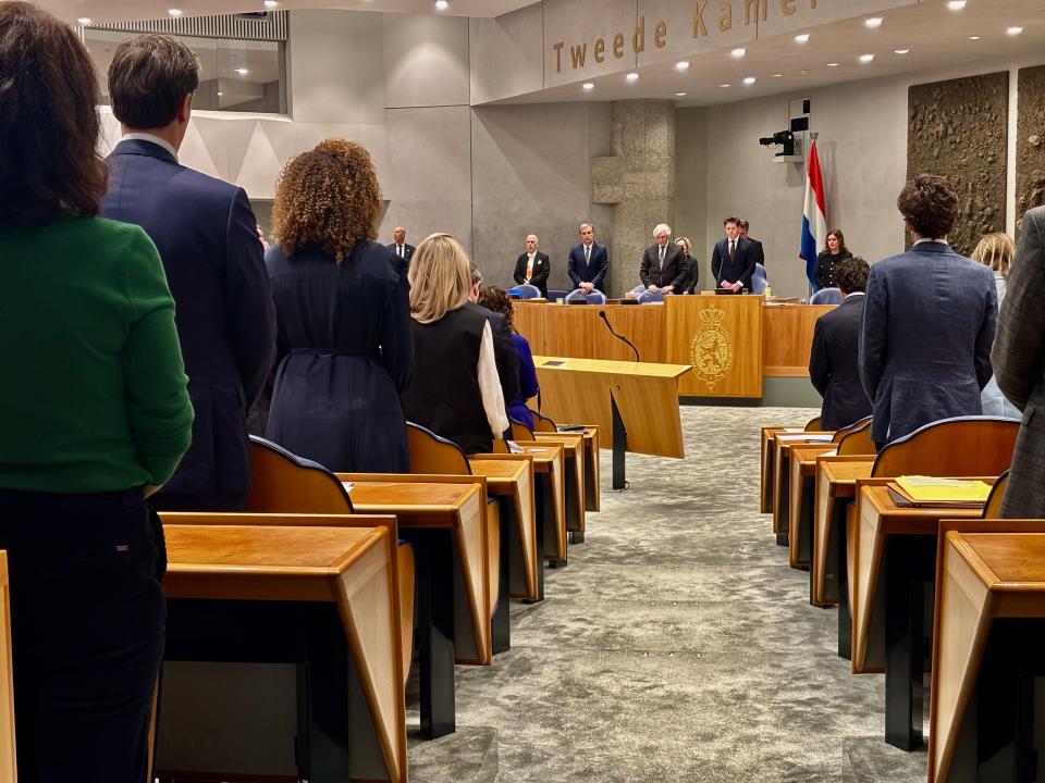 Iedereen in de plenaire zaal staat om de aanslag van afgelopen zondag in Australië te herdenken. Kamerleden op de rug gezien, in het midden van de foto de Voorzitter en anderen in het Voorzittersgestoelte. 