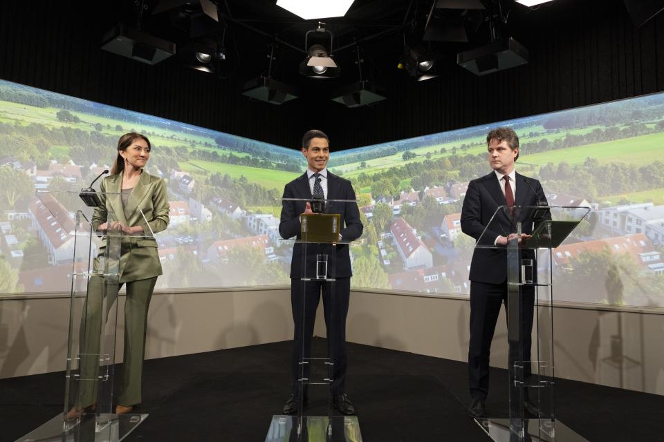 De drie fractievoorzitters achter drie katheders tegen een achterwand met luchtfoto van Nederland. Van links naar rechts Dilan Yeşilgöz (VVD), Rob Jetten (D66) en Henri Bontenbal (CDA). 