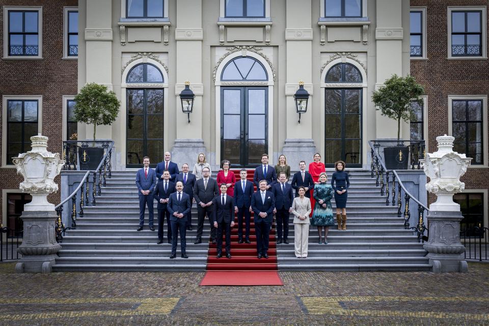 De nieuwe ministers staan verspreid rond Koning Willem-Alexander op de trappen van Paleis Huis ten Bosch. 