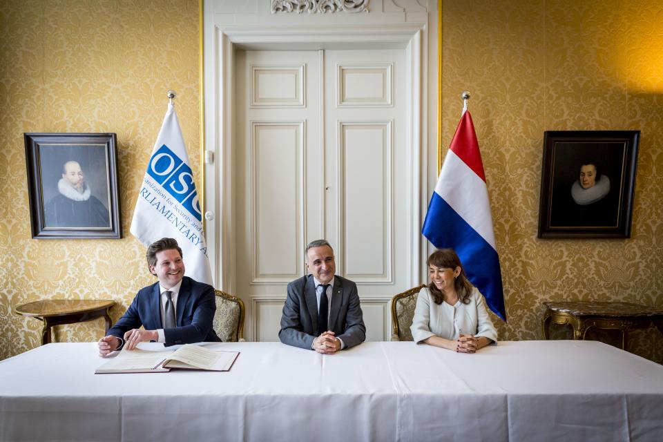 Van links naar rechts zitten Kamervoorzitter Thom van Campen, OVSE PA-voorzitter Pere Joan Pons Sampietro en Eerste Kamervoorzitter Mei Li Vos aan een tafel. Thom van Campen tekent een document.