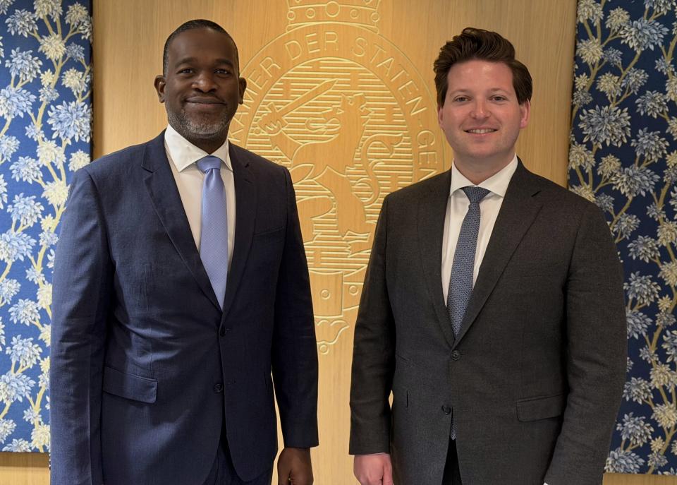 Links staat gouverneur Ajamu Baly, rechts Kamervoorzitter Thom van Campen. Op de achterwand staat het wapen van de Tweede Kamer.