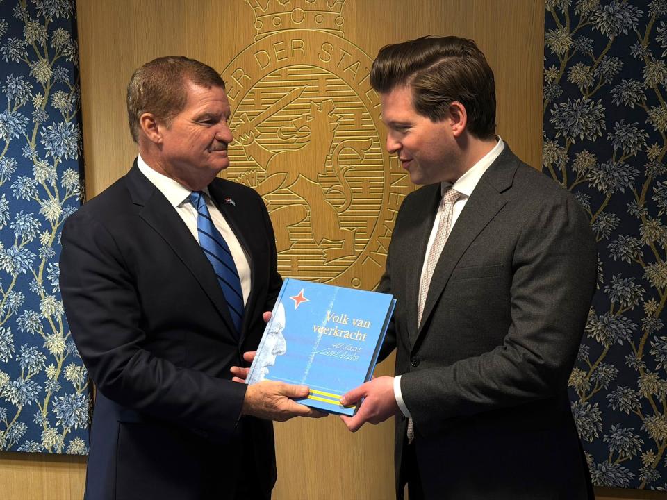De premier van Aruba, Mike Eman, overhandigt het boek 'Volk van veerkracht' aan Kamervoorzitter Thom van Campen.