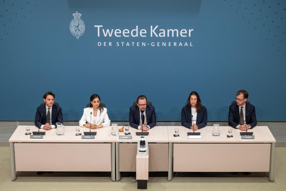 Voltallige commissie, vijf mensen, op een rij achter de tafels in de Enquêtezaal. 