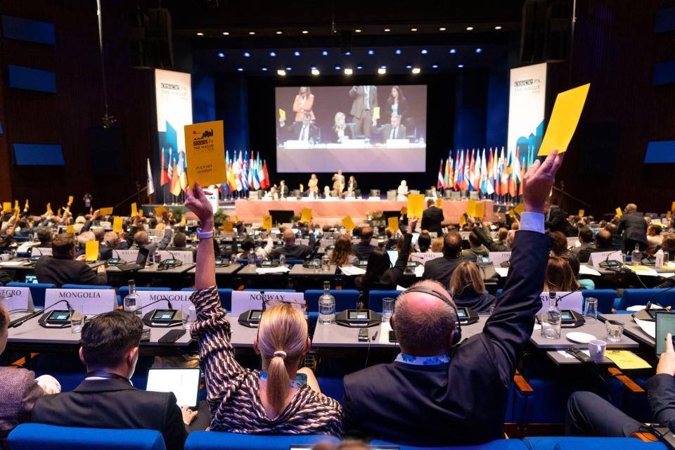 Parlementsleden stemmen door het omhooghouden van briefjes in de plenaire zaal van het World Forum.