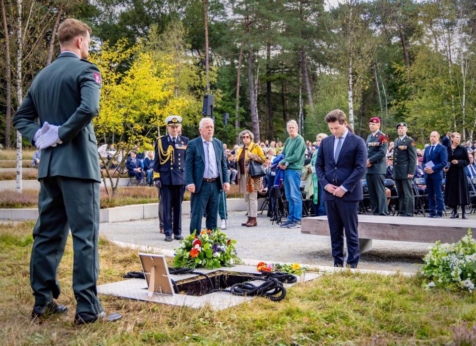 Kamervoorzitter Thom van Campen staat gebogen voor een oorlogsgraf. Tegenover hem staat een militair.