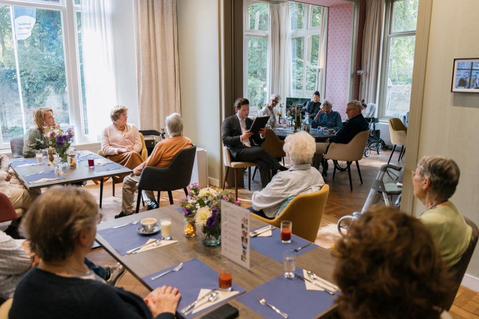 De Kamervoorzitter leest een verhaal voor aan ouderen.