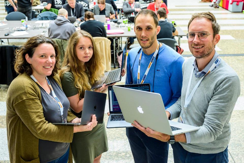 Linda, Chayenne, Pieter en Elze staan dicht bij elkaar en houden allemaal een laptop vast