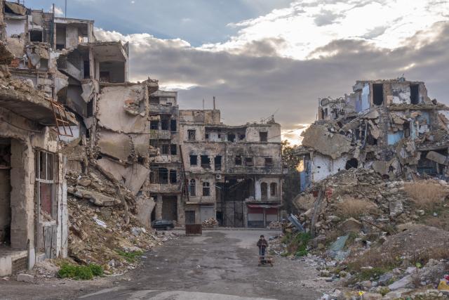Ingestorte huizen in Aleppo, Syrië. Tussen het puin loopt een kind.