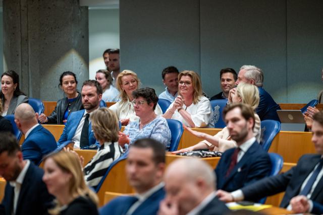Christianne van der Wal zit op haar zetel in de plenaire zaal. Ze heeft haar handen ineen geslagen. Om haar heen zitten haar fractiegenoten.