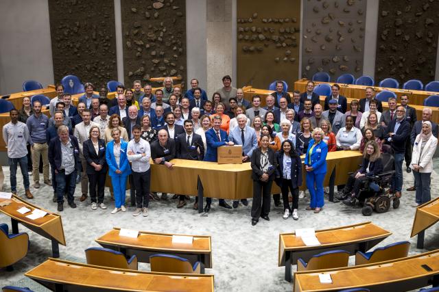 Kamervoorzitter Martin Bosma en Griffier Peter Oskam met de deelnemers aan de V-100 in 2025 in de plenaire zaal.