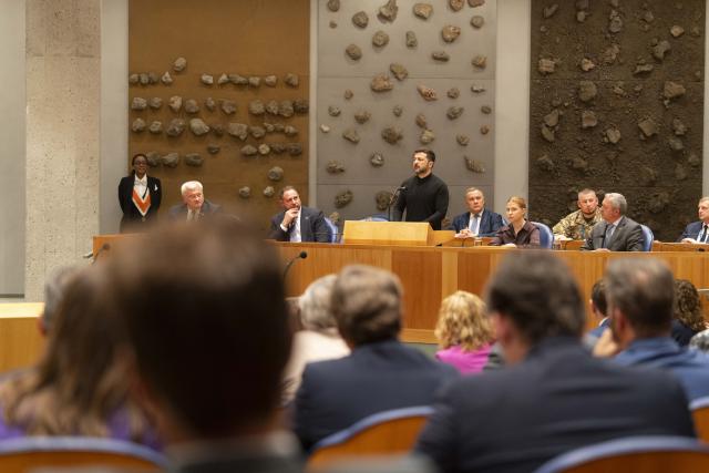 De Oekraïense president Zelensky spreekt vanaf de plek waar normaal gesproken bewindspersonen het woord voeren. Op de voorgrond de Kamerleden in de plenaire zaal. 