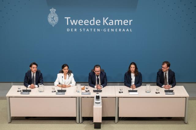 Voltallige commissie, vijf mensen, op een rij achter de tafels in de Enquêtezaal. 