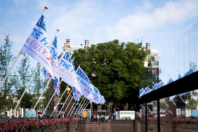 Vlaggen aan de hofvijver met het logo van de jaarvergadering van de OVSE PA.